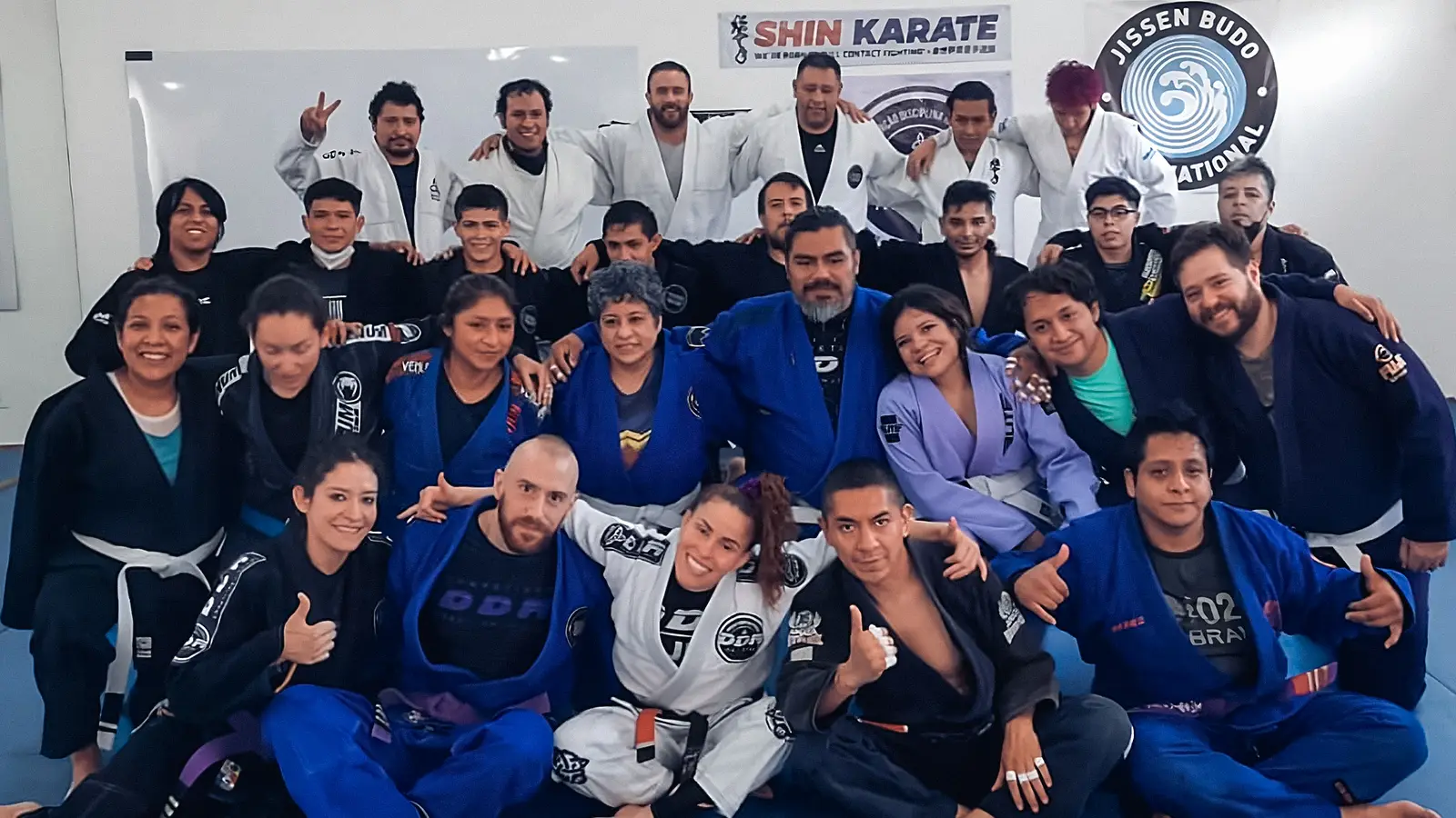 instructores y alumnos de jiu jitsu brasileño sentados de frente a la cámara